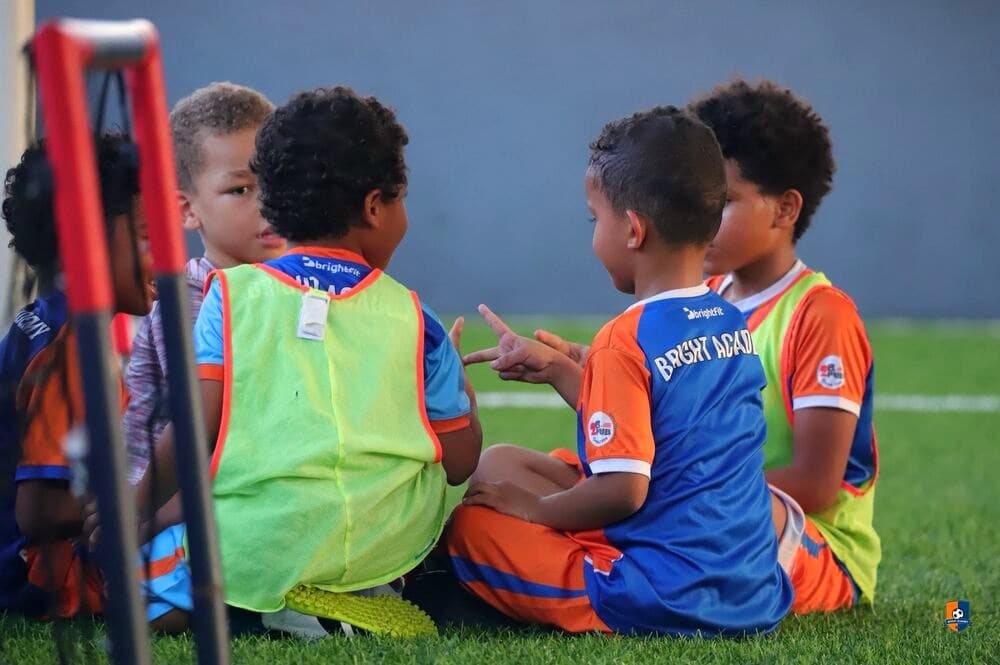 Bright Academy players in training bibs chatting together on the pitch