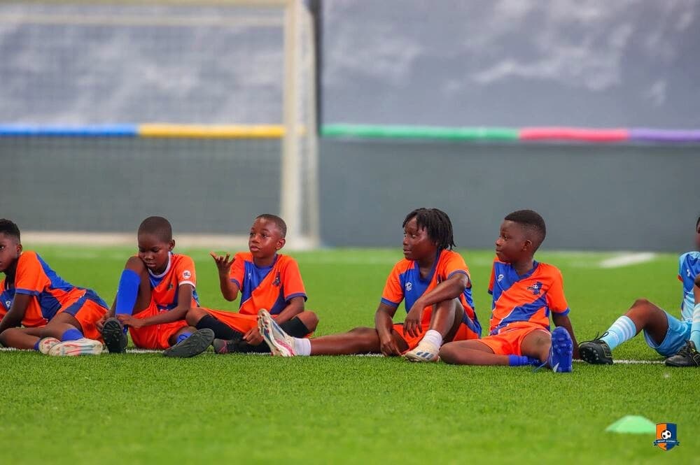Bright Academy players sitting together pitch-side near the goal