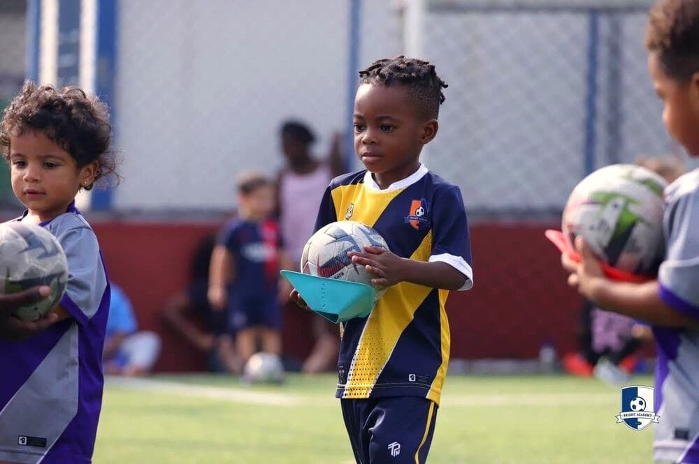 Young Bright Academy players holding footballs before a session