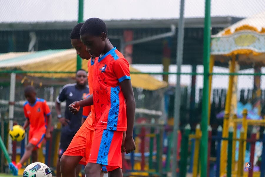 Bright Academy player in orange kit focused on the ball