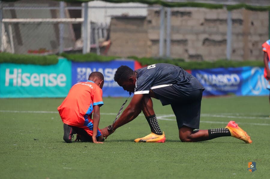 A Bright Academy coach helping a young player with their boots